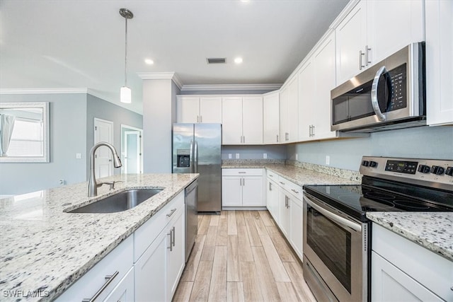 kitchen featuring sink, hanging light fixtures, stainless steel appliances, white cabinets, and crown molding