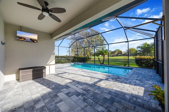 view of pool featuring a patio, glass enclosure, and ceiling fan