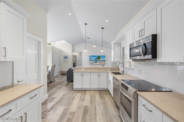 kitchen with appliances with stainless steel finishes, white cabinetry, light hardwood / wood-style flooring, pendant lighting, and sink