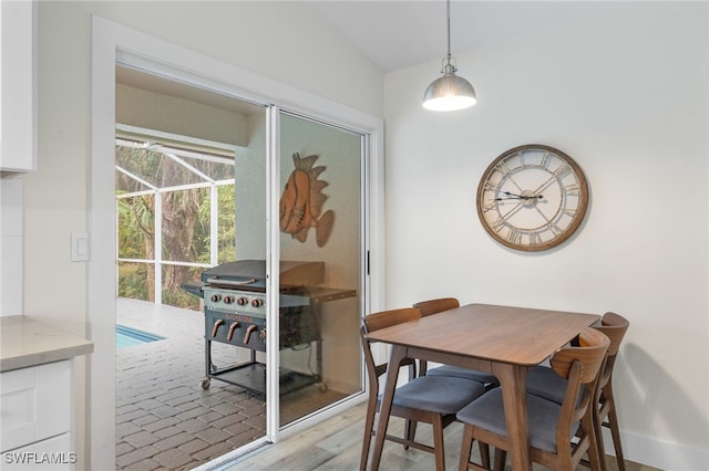 dining area with vaulted ceiling and light hardwood / wood-style flooring