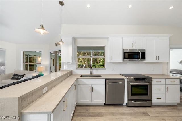 kitchen featuring appliances with stainless steel finishes, decorative light fixtures, light wood-type flooring, and white cabinets