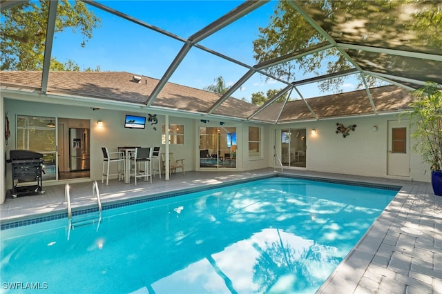 view of swimming pool featuring a patio, a lanai, and a grill