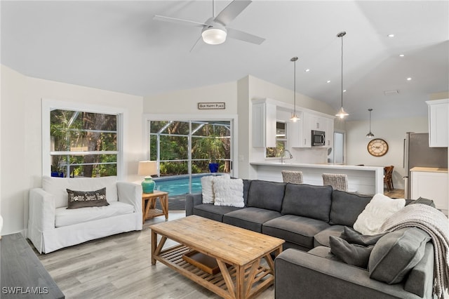 living room featuring light hardwood / wood-style flooring, vaulted ceiling, and ceiling fan