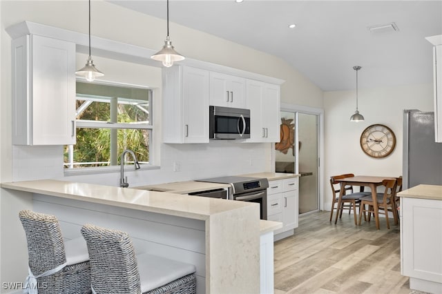 kitchen featuring lofted ceiling, appliances with stainless steel finishes, pendant lighting, and white cabinets