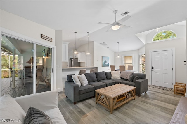 living room featuring lofted ceiling, light wood-type flooring, and ceiling fan