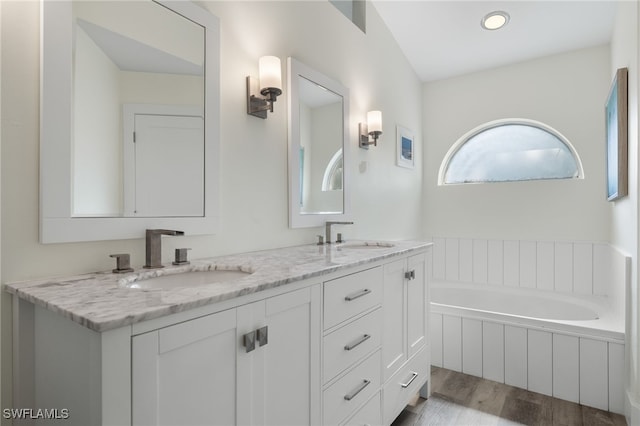 bathroom featuring vanity, a relaxing tiled tub, and hardwood / wood-style floors