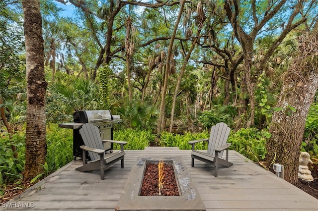 wooden terrace with an outdoor fire pit and a grill