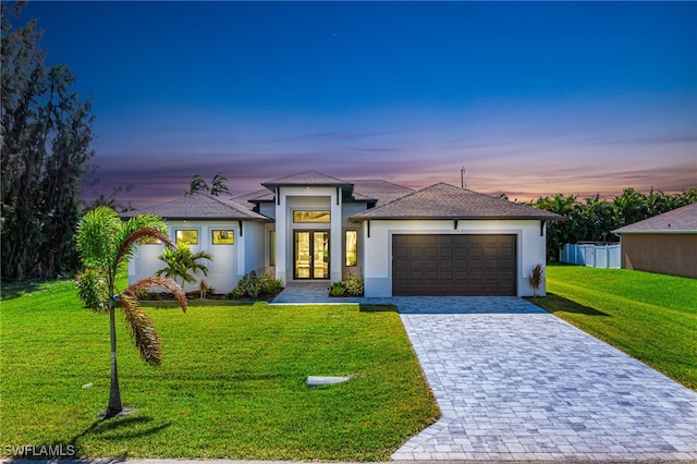 view of front of property featuring a lawn, a garage, and french doors