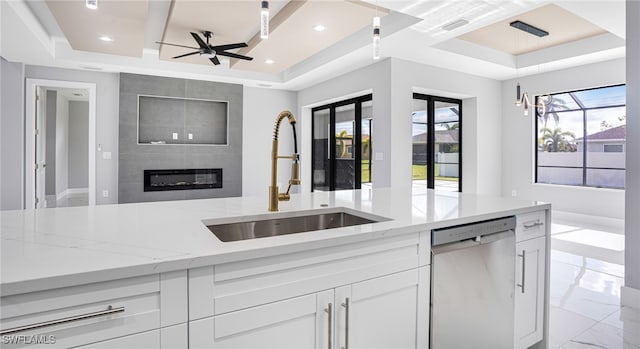 kitchen featuring stainless steel dishwasher, white cabinets, sink, and a tray ceiling