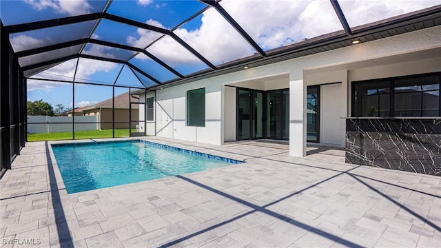 view of pool with glass enclosure and a patio