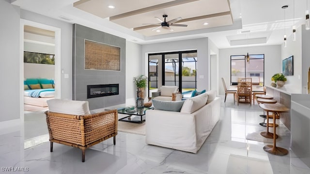 living room featuring a fireplace, a tray ceiling, and ceiling fan