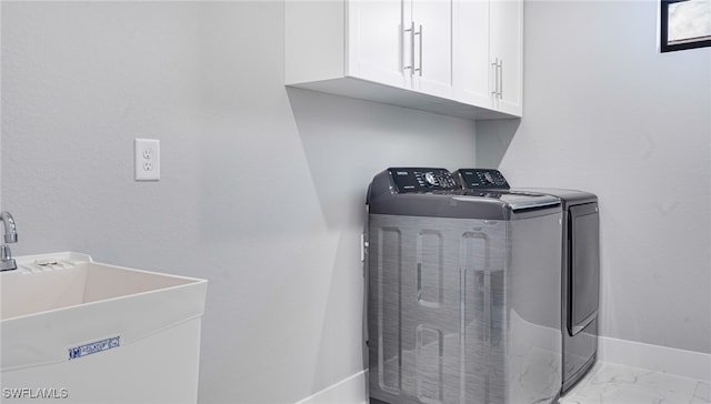 clothes washing area featuring cabinets, washing machine and dryer, and sink