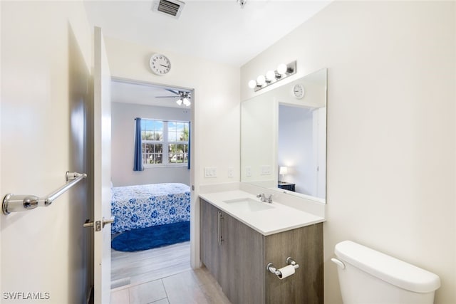 bathroom featuring toilet, vanity, hardwood / wood-style floors, and ceiling fan