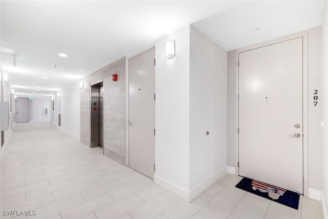 hallway featuring elevator and light tile patterned flooring