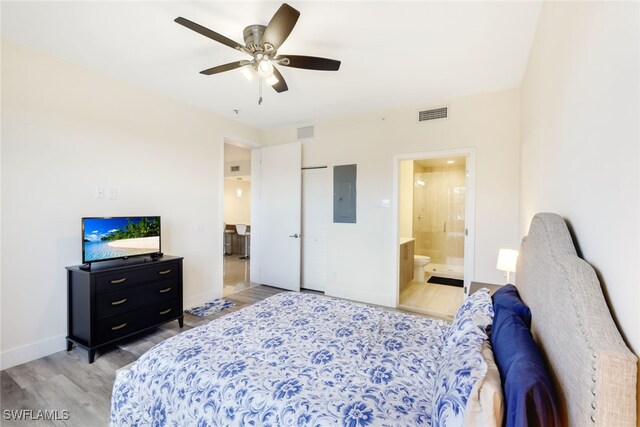 bedroom featuring a closet, electric panel, connected bathroom, ceiling fan, and light hardwood / wood-style flooring