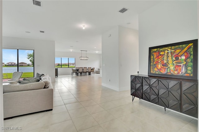 living room featuring a water view, an inviting chandelier, and light tile patterned floors