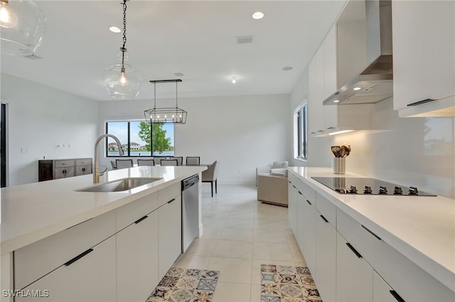 kitchen with black electric stovetop, wall chimney range hood, sink, white cabinetry, and pendant lighting