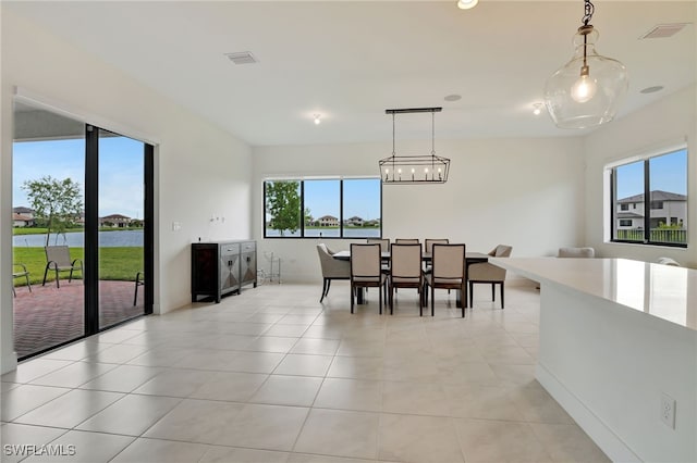 dining room featuring light tile patterned floors, a water view, and a wealth of natural light