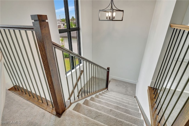 staircase featuring a chandelier, carpet, a towering ceiling, and plenty of natural light