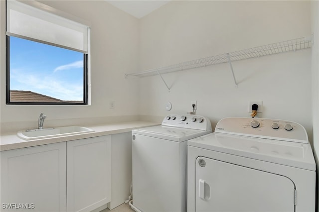 clothes washing area with cabinets, sink, and washer and clothes dryer