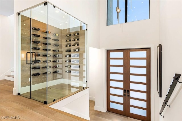 wine area with hardwood / wood-style floors and a towering ceiling