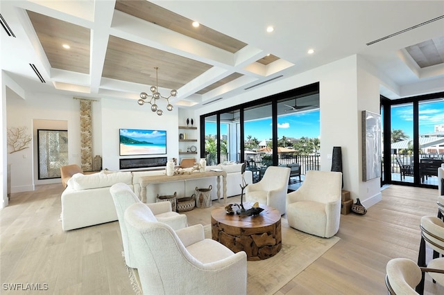 living room with an inviting chandelier, light hardwood / wood-style flooring, coffered ceiling, and a healthy amount of sunlight