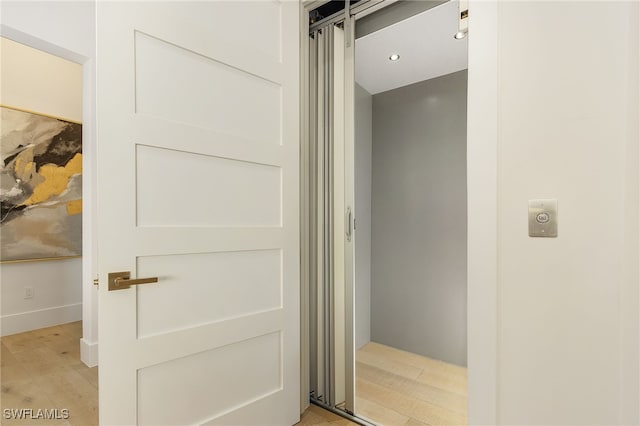 bathroom with elevator and hardwood / wood-style floors