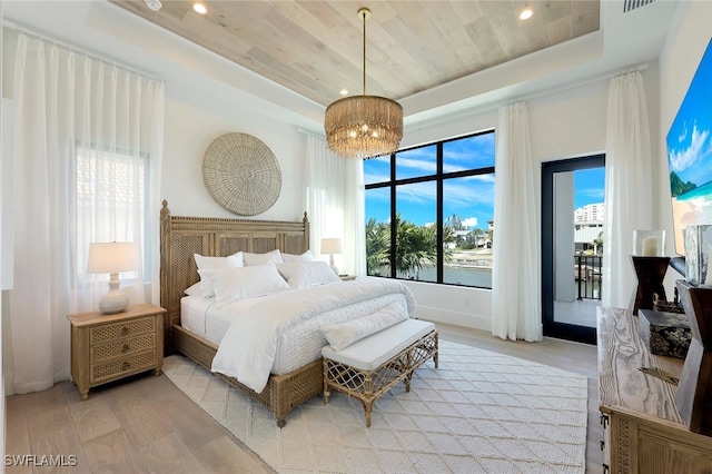 bedroom featuring wood ceiling, an inviting chandelier, a raised ceiling, and light hardwood / wood-style floors