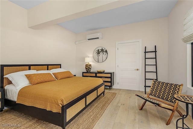 bedroom with an AC wall unit and light wood-type flooring