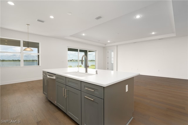 kitchen featuring gray cabinetry, a center island with sink, dishwasher, sink, and dark hardwood / wood-style floors