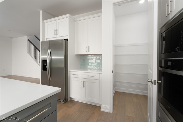 kitchen with hardwood / wood-style floors, white cabinetry, stainless steel appliances, and tasteful backsplash