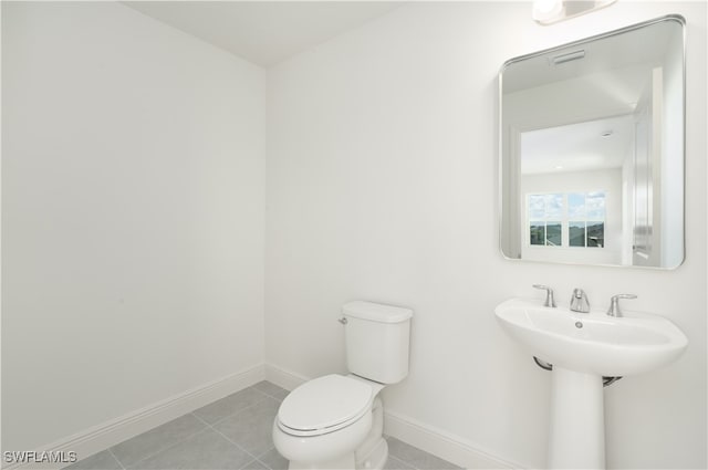 bathroom featuring toilet, sink, and tile patterned flooring