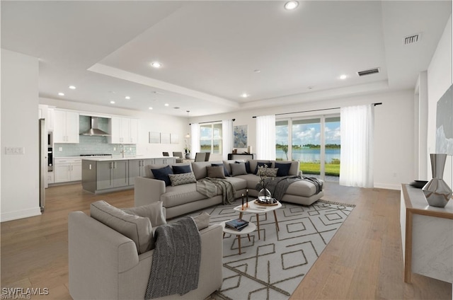 living room with light hardwood / wood-style flooring and a tray ceiling