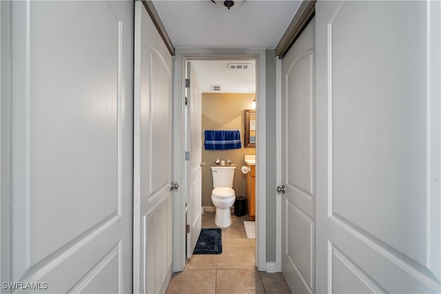 hall with a textured ceiling and light tile patterned floors