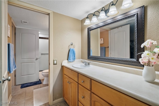 bathroom featuring vanity, a textured ceiling, toilet, and tile patterned floors