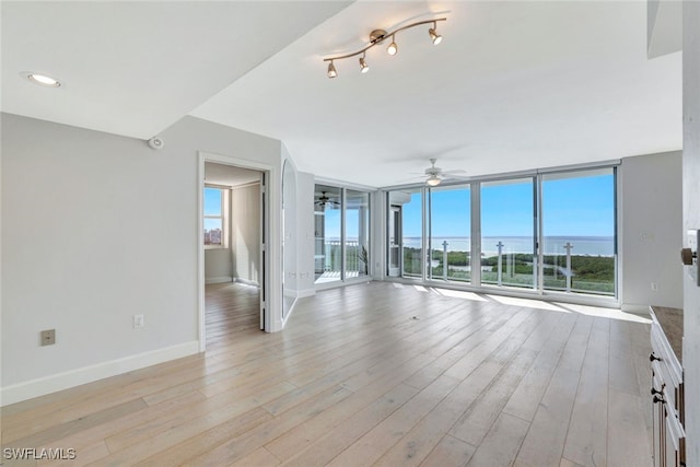 unfurnished living room featuring a wealth of natural light, ceiling fan, and light hardwood / wood-style flooring