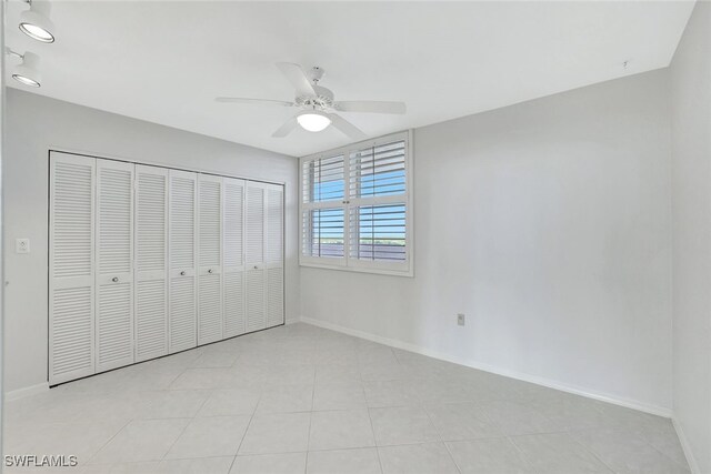 unfurnished bedroom with a closet, light tile patterned floors, and ceiling fan