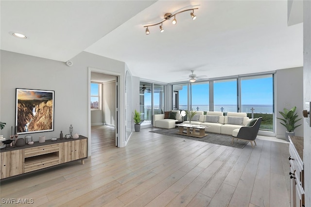 living room featuring light wood-type flooring, a water view, and ceiling fan