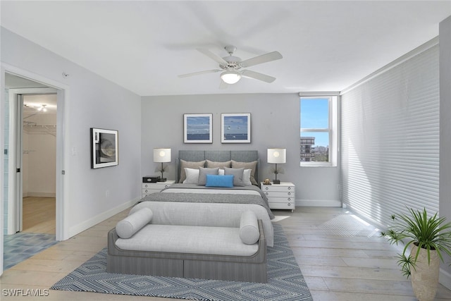 bedroom featuring light hardwood / wood-style floors, ceiling fan, a closet, and a walk in closet