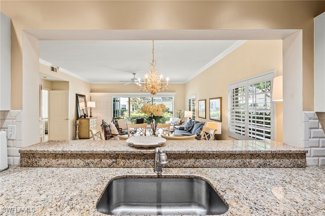 kitchen with a wealth of natural light, sink, light stone counters, and ornamental molding