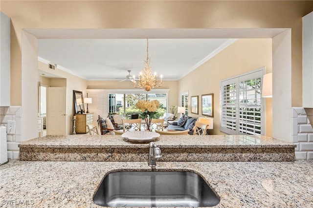 kitchen with ornamental molding, a notable chandelier, light stone countertops, and a sink