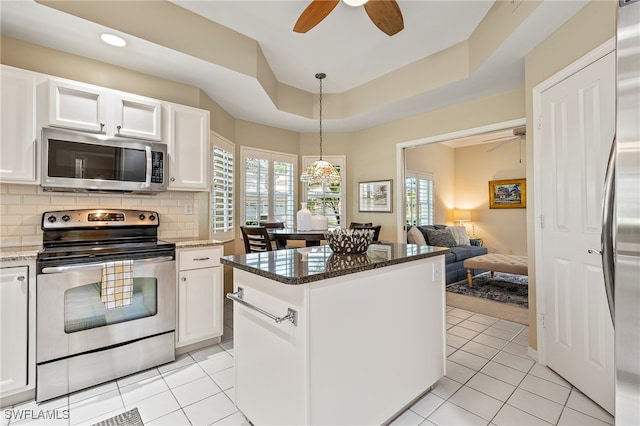 kitchen featuring white cabinets, appliances with stainless steel finishes, plenty of natural light, and dark stone countertops