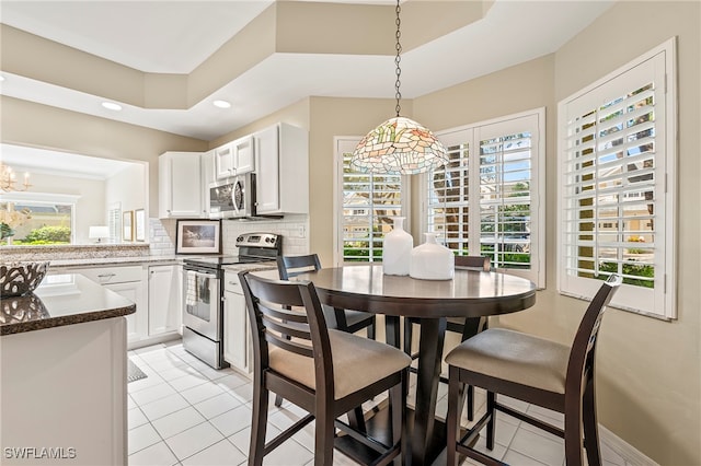 tiled dining room with a tray ceiling and a notable chandelier