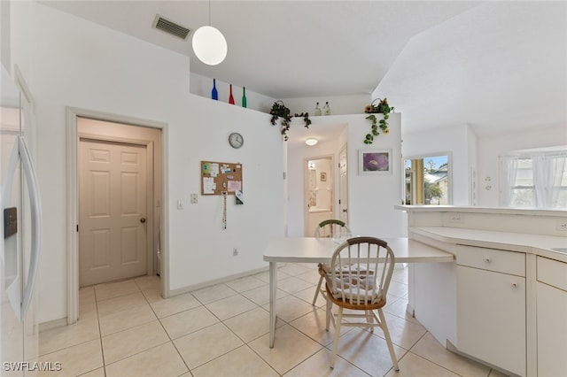 kitchen with light tile patterned floors, pendant lighting, and white refrigerator with ice dispenser