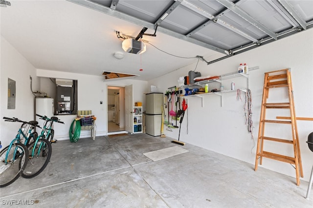 garage featuring heating unit, water heater, white refrigerator, electric panel, and a garage door opener