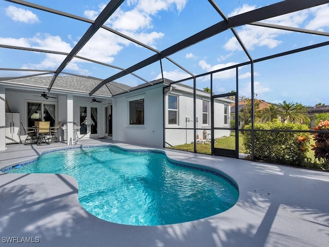 view of pool featuring glass enclosure, a patio area, and ceiling fan