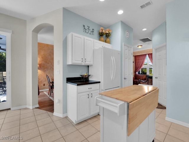 kitchen with white cabinets, light tile patterned floors, a center island, and white fridge