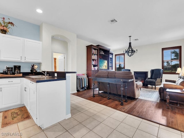 kitchen with white cabinets, light hardwood / wood-style floors, pendant lighting, and kitchen peninsula