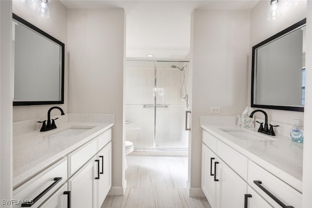 bathroom with toilet, vanity, and a shower with door