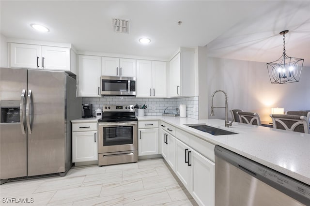 kitchen with sink, white cabinetry, stainless steel appliances, decorative light fixtures, and an inviting chandelier